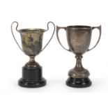 Two silver twin handled trophies, hallmarked London 1934 and 1939, raised on black Bakelite