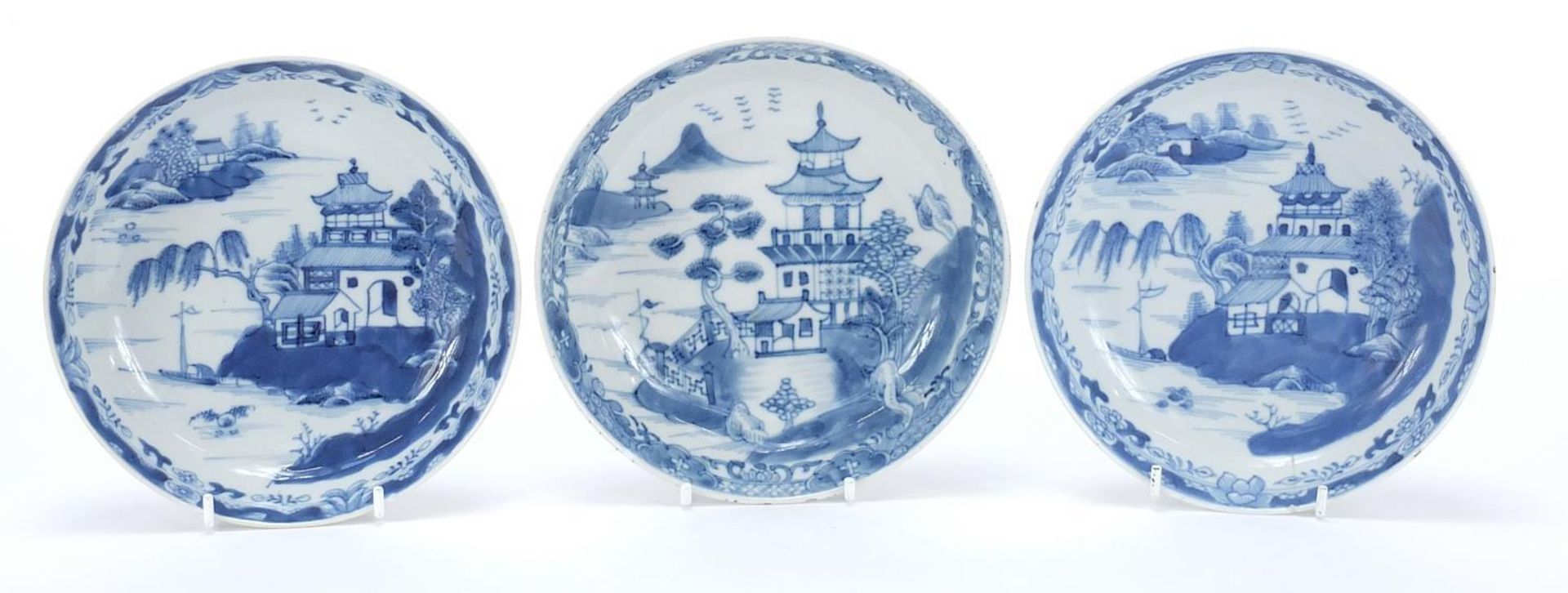 Three Chinese blue and white porcelain dishes each hand painted with a pagoda and river landscape,