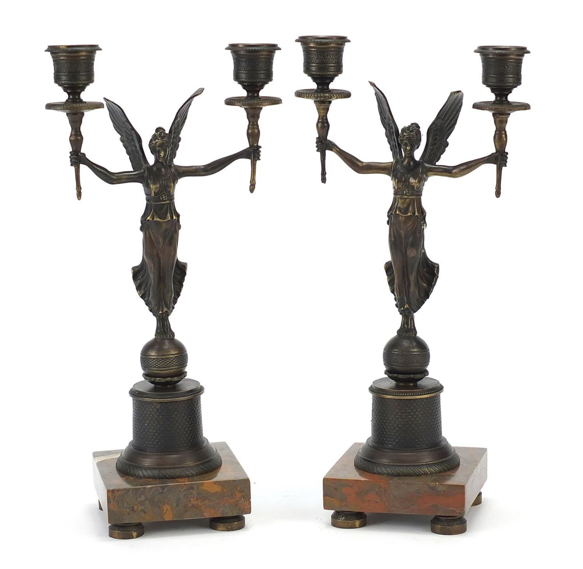 Pair of classical patinated bronze figural two branch candlesticks raised on square marble bases,