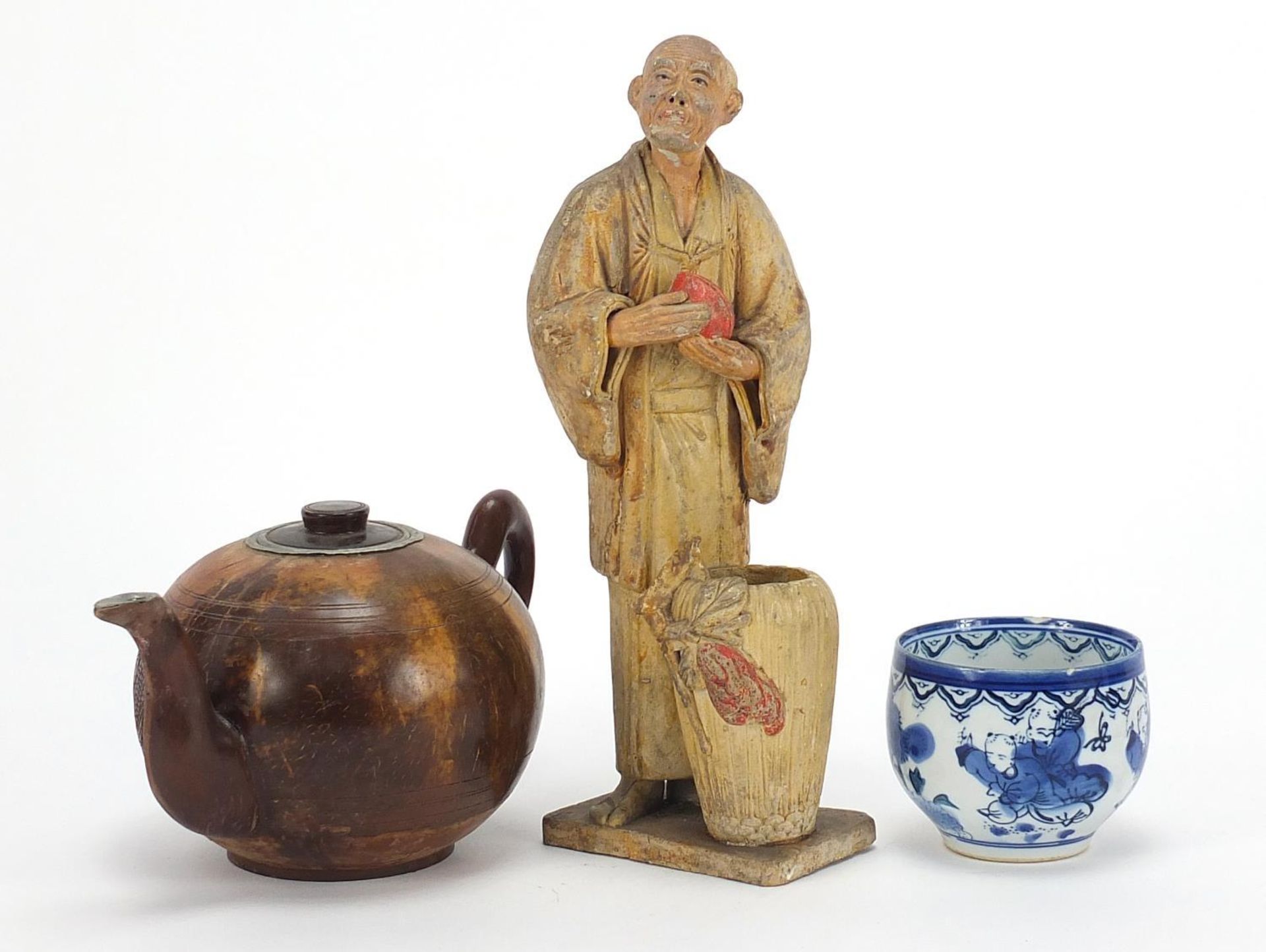 Oriental objects including a carved wood teapot and pottery figure of a man holding a peach, the