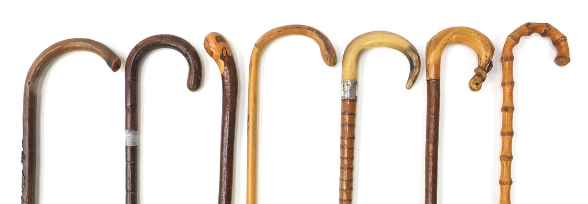 Six walking sticks and a vintage parasol, including two with horn handles and one with silver