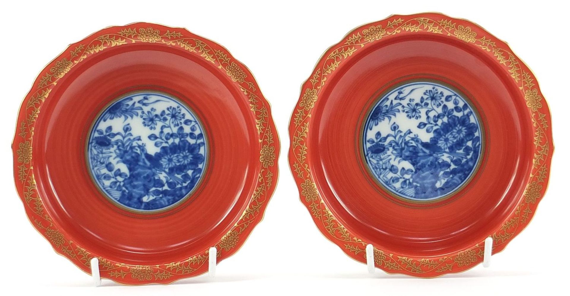 Pair of Japanese iron red ground porcelain dishes hand painted and gilded with flowers, each with