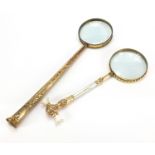 Two large antique gilt metal magnifying glasses including one with mother of pearl handles, the