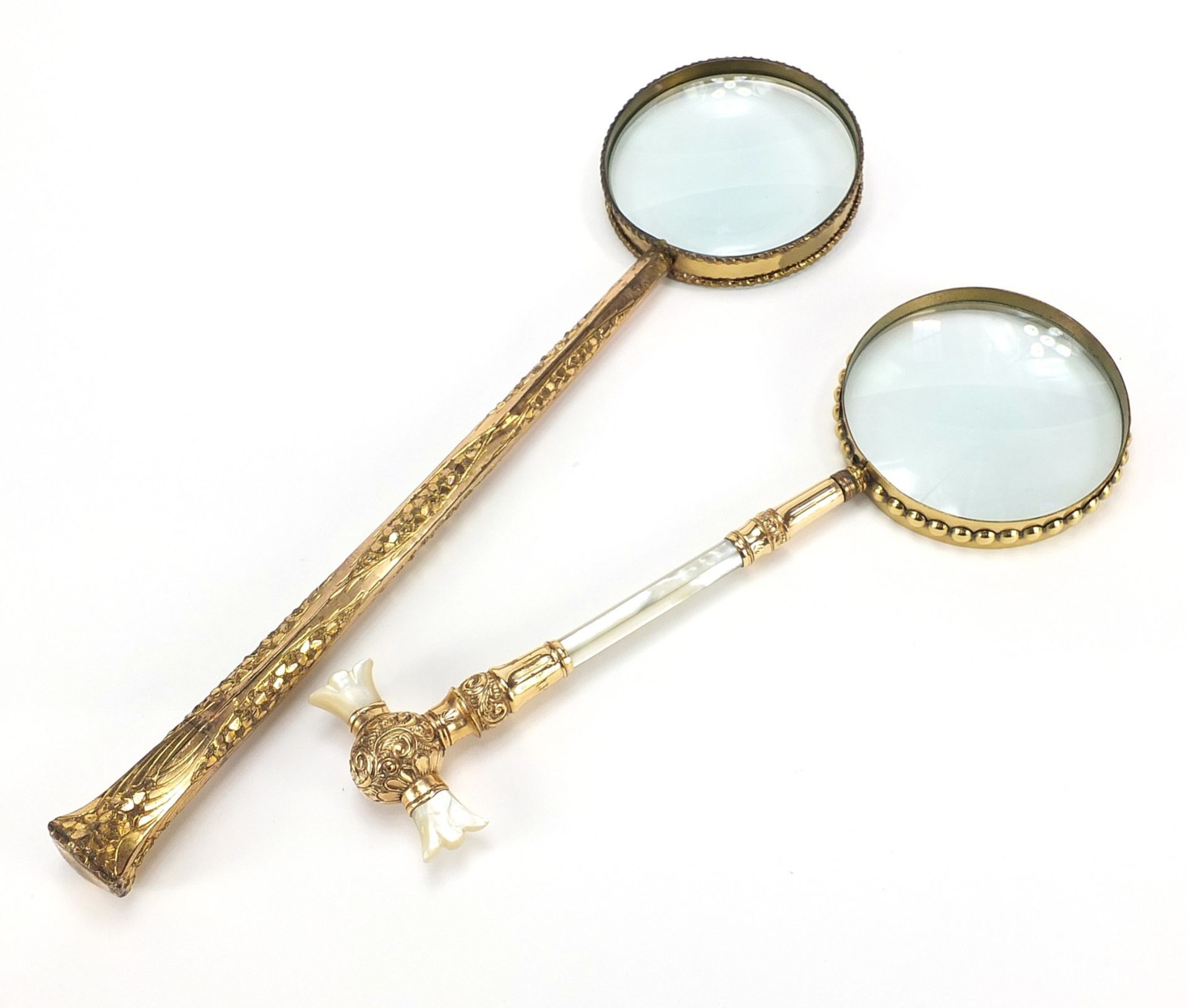 Two large antique gilt metal magnifying glasses including one with mother of pearl handles, the