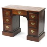Inlaid oak knee hole desk with tooled leather insert, an arrangement of seven drawers and ornate