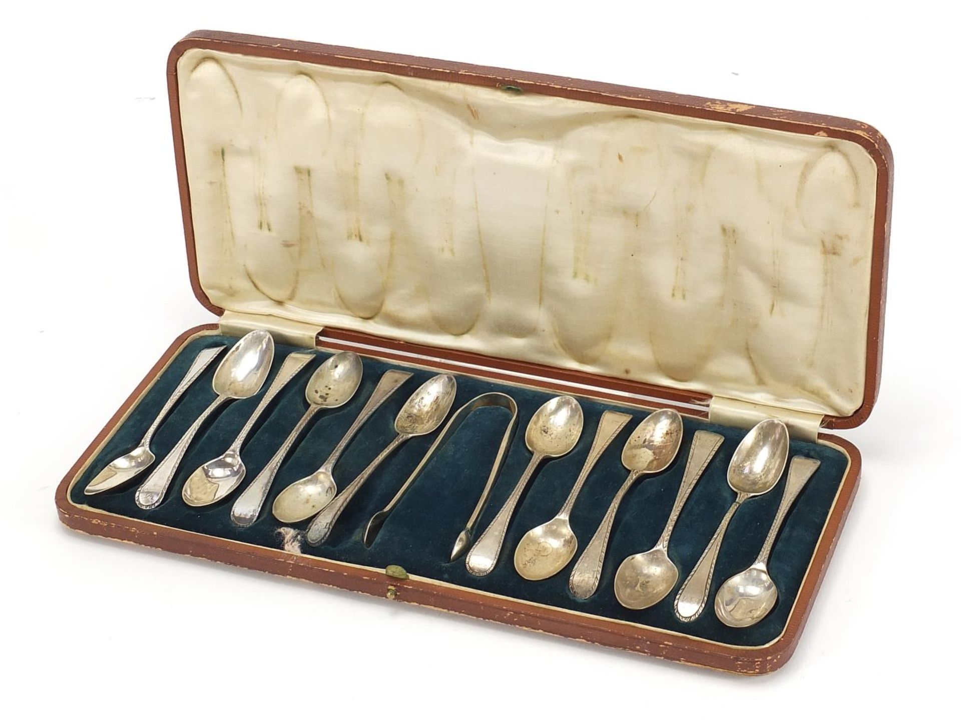 Matched set of twelve silver teaspoons and silver plated sugar tongs housed in a velvet and silk