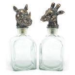 Pair of glass decanters with bronzed rhinoceros and giraffe head design stoppers, each 25cm high :