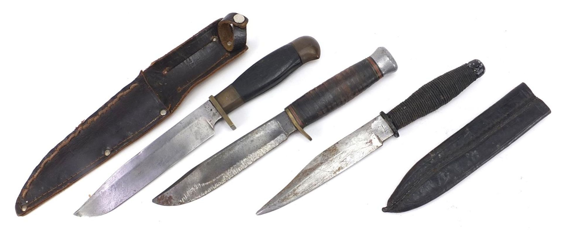 Three military interest hunting/combat knives including two with leather sheaths, the largest 27cm