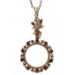 Silver marcasite and garnet cherub magnifying glass pendant, on a silver coloured metal necklace,