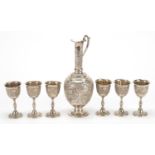 Persian silver coloured metal jug and six glasses profusely embossed and engraved with birds amongst