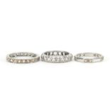 Three unmarked white metal clear stone eternity rings, sizes I and M, 6.4g : For Further Condition