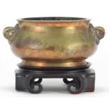 Large Chinese patinated bronze censer with animalia handles raised on a carved hardwood stand, six