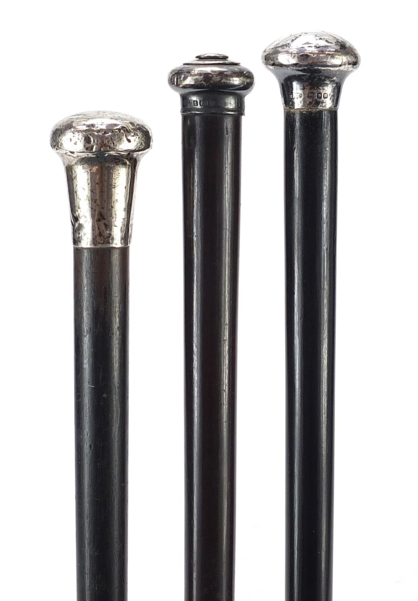Three ebonised walking sticks with silver pommels, the largest 92cm in length : For Further