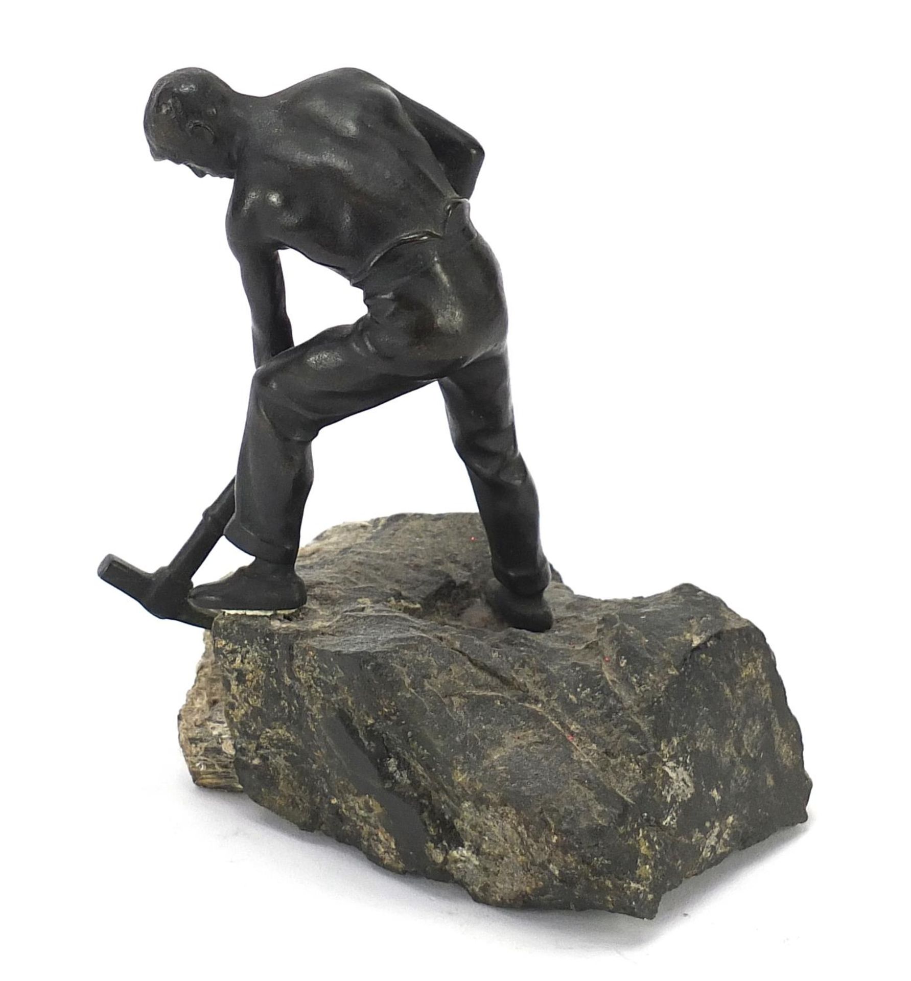 Patinated bronze sculpture of a semi nude man with a pickaxe raised on a naturalistic stone base, - Image 2 of 3
