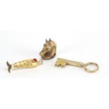 Three gold coloured metal charms comprising key, horse head and fish, the largest 3.8cm in length,