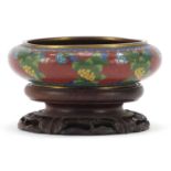 Chinese cloisonne squatted bowl enamelled with flowers raised on carved hardwood stand, 13.5cm in