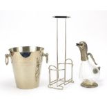 Vintage items comprising a duck design claret jug, 1970's bottle stand and Champagne ice bucket, the