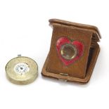 Early 20th century leather cased travelling clock with enamelled love heart shaped aperture, the