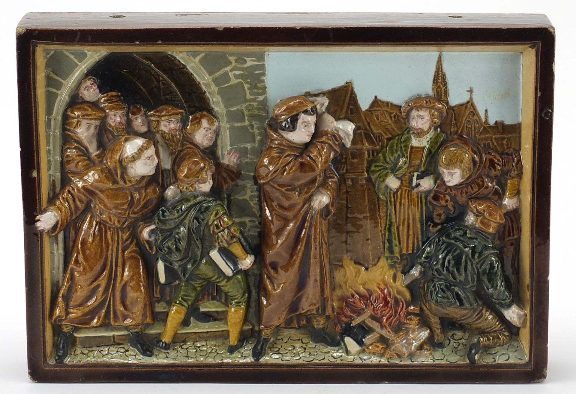 19th century Continental stoneware plaque decorated in relief with religious zealots burning