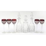 Three cut glass decanters with stoppers and a set of five ruby flashed cut glass glasses, the