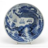 Chinese blue and white porcelain bowl hand painted with a dragon amongst clouds above waves, blue