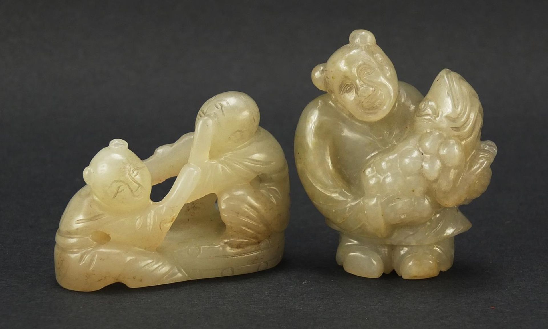 Two Chinese celadon and russet jade carvings including one of a figure holding fruit, the largest