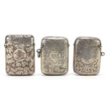 Two Victorian and later silver vestas and a silver coloured metal example, each engraved with vines,