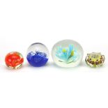 Four glass paperweights including one star design with colourful canes, the largest 8.5cm in