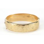 9ct gold hinged bangle with engraved decoration, Birmingham 1994, 6.2cm in diameter, 1.5cm wide,