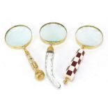 Three magnifying glasses including one with chequered design handle, the largest 27.5cm in