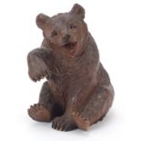 Carved Black Forest seated bear with raised paw and open mouth, 14cm high