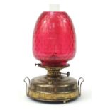 Large brass oil lamp with cranberry shade, 50cm high