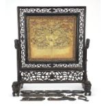 Chinese carved hardwood table screen housing a rank badge embroidered with a dragon amongst