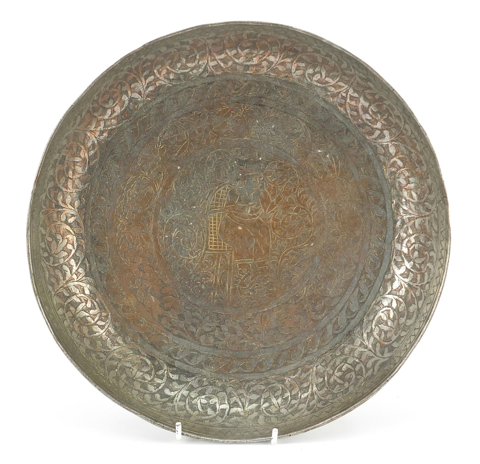 Turkish silvered copper dish engraved with a figure seated in the centre surrounded by flowers and
