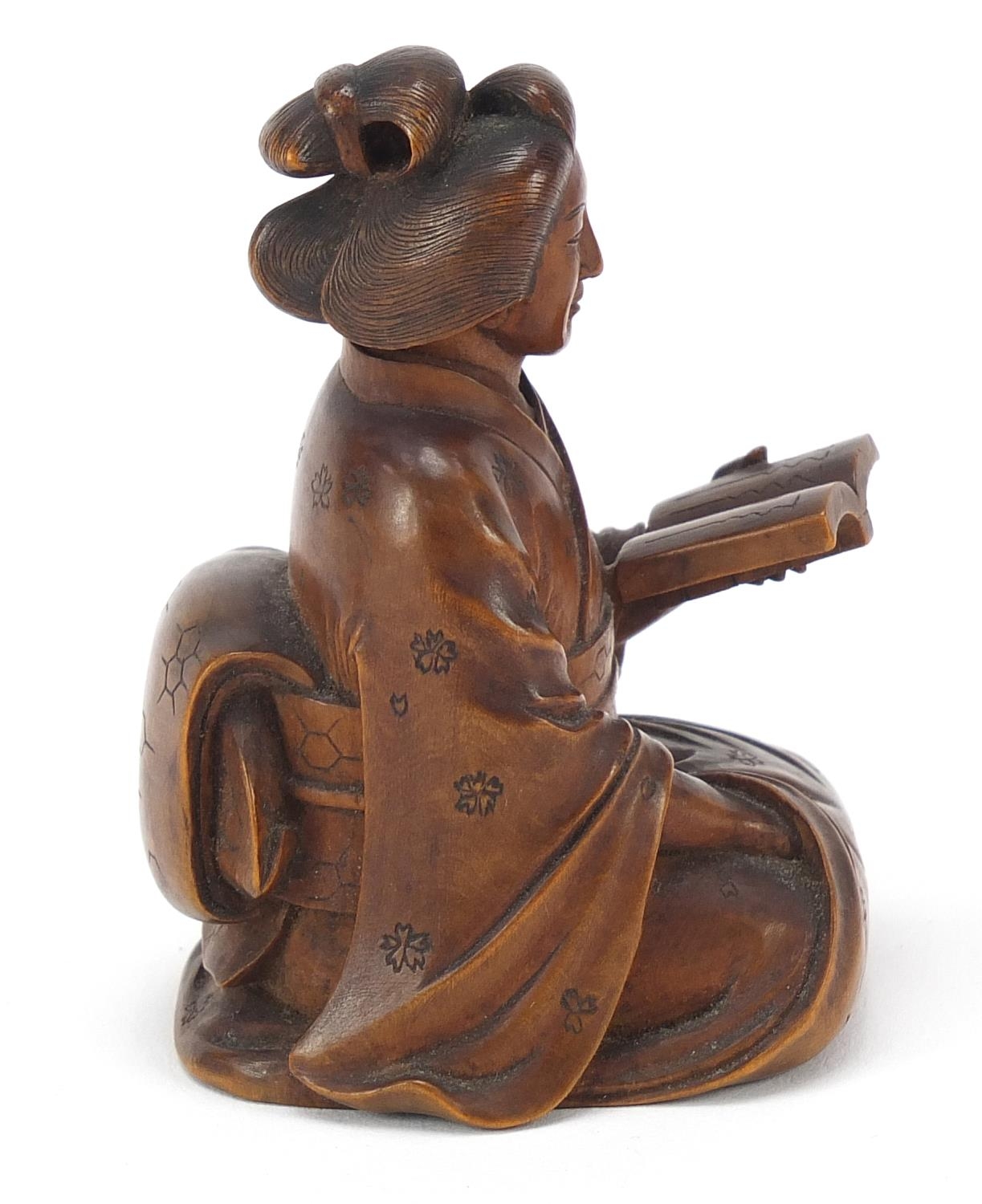 Japanese erotic carved hardwood okimono of a lady kneeling down reading a book, character mark to - Image 5 of 8