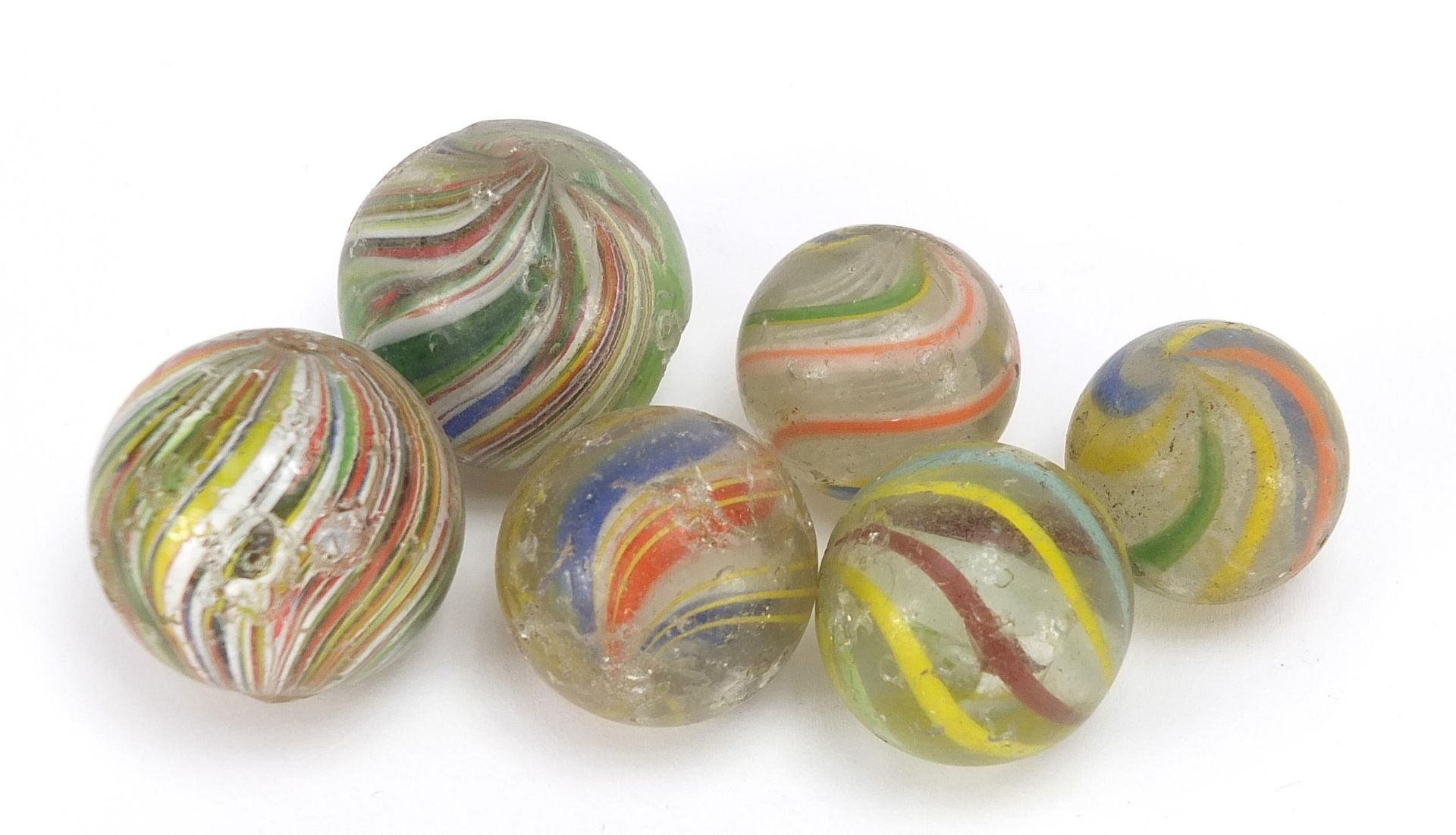 Six antique coloured swirl glass marbles, the largest approximately 3.5cm in diameter