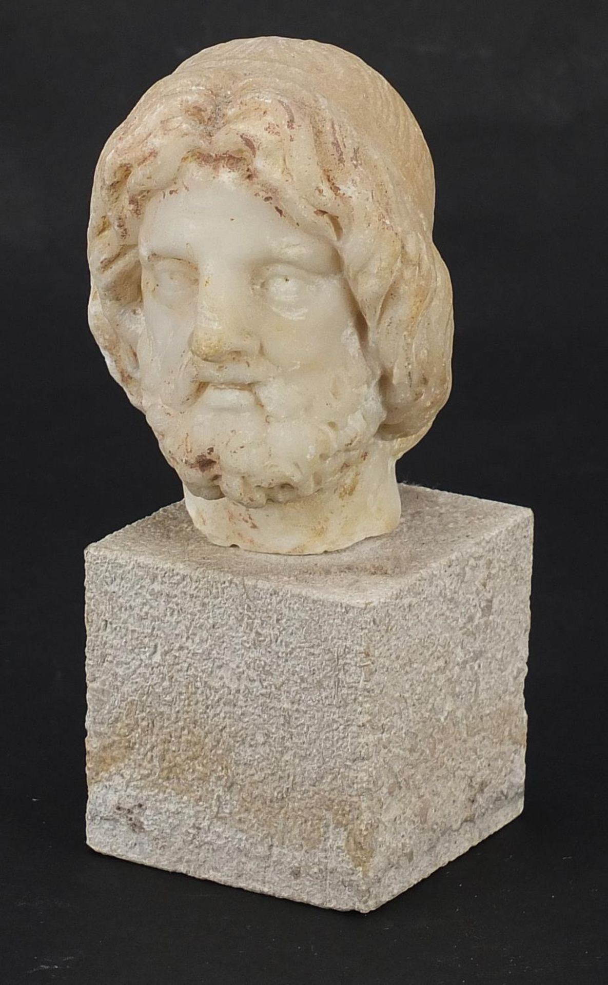 Antique carved white marble bust of a bearded man raised on a square block base, possibly Roman or