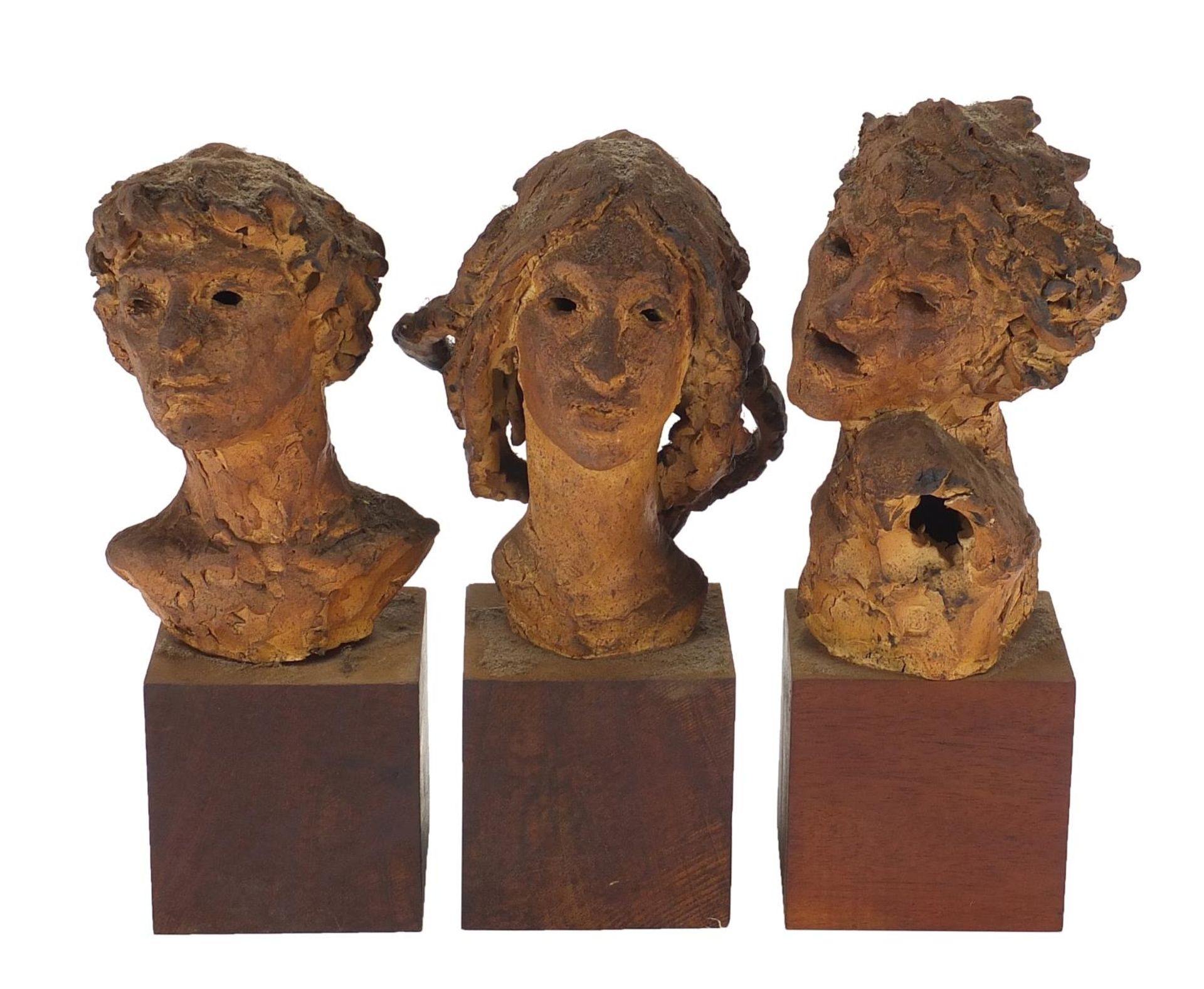 Three mid century pottery busts raised on wooden block bases, each inscribed Elizabeth Benenson to