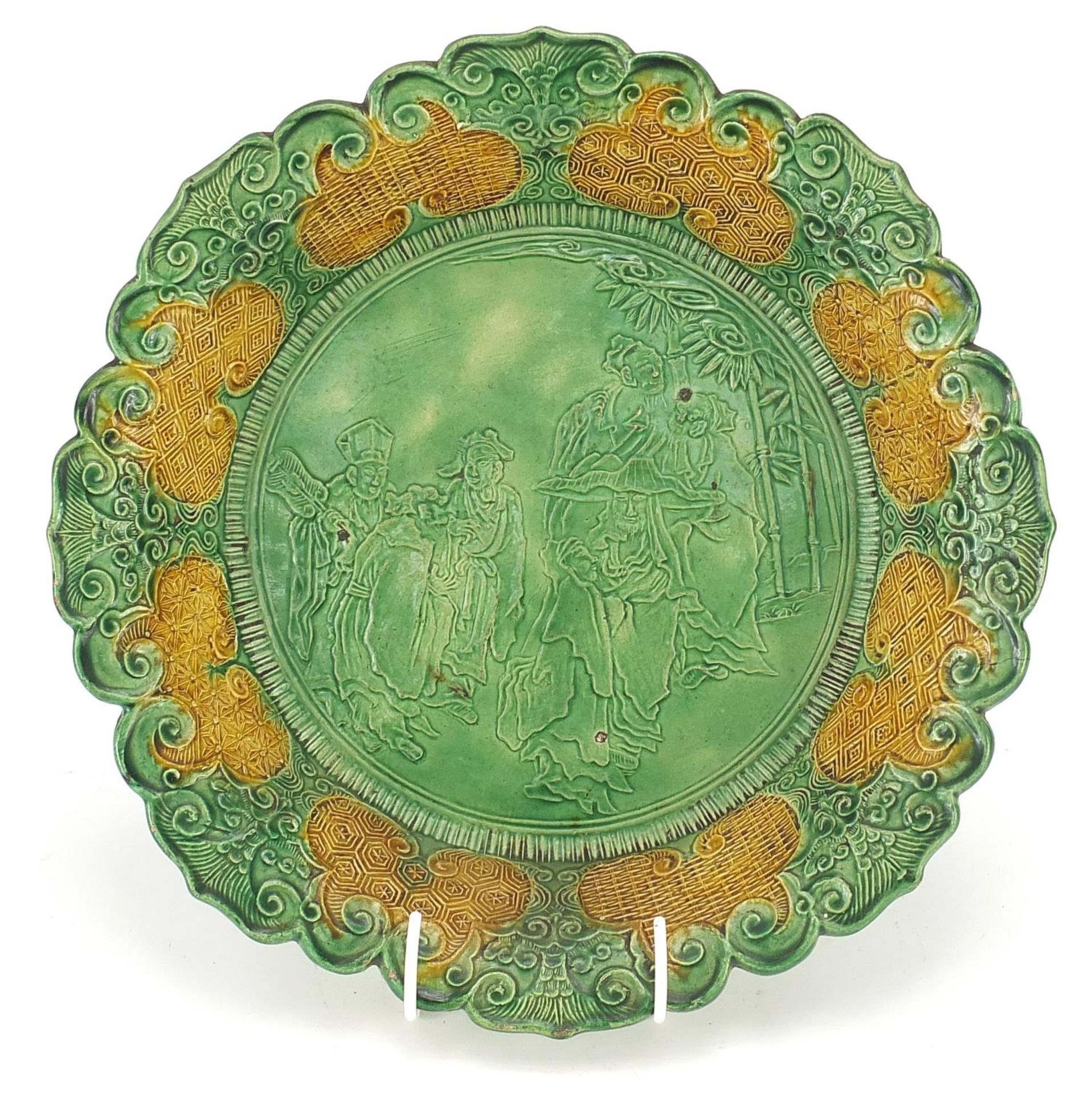 Chinese green and yellow glazed porcelain dish decorated in relief with figures in a palace setting,