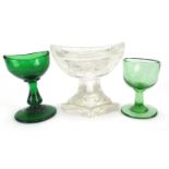 Two Georgian green glass eye baths and a cut glass salt, the largest 8cm high