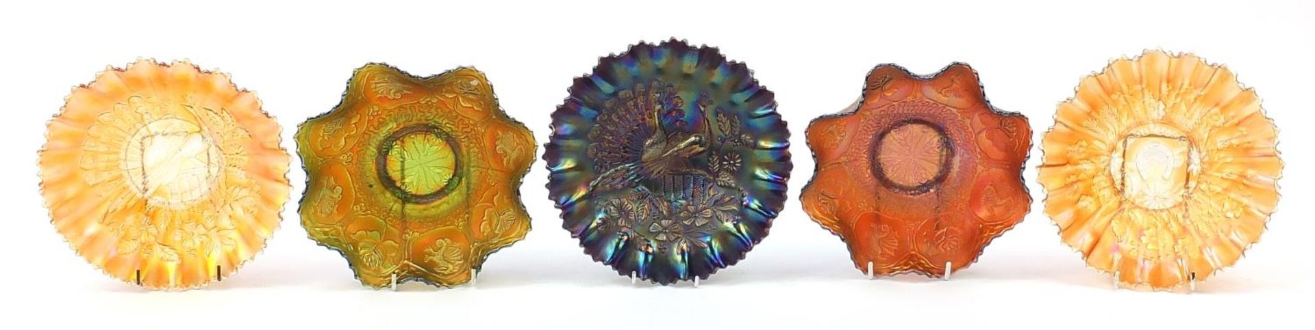 Five Victorian carnival glass dishes to include two with peacocks on a fence, two with dragons and a