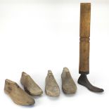 Four antique wooden shoe lasts and a bootmaker's last, the largest 56cm high