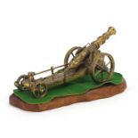 Brass model gun carriage mounted on a wooden plinth, 30cm wide