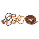 Two amber coloured necklaces and a nut necklace, the largest 80cm in length, total 142.6g