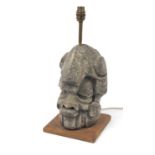 Heavy large reconstituted stone desk lamp in the form of an Aztec style face standing on a wooden