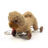 Vintage pull along dog mounted on a wheeled base, 35cm in length