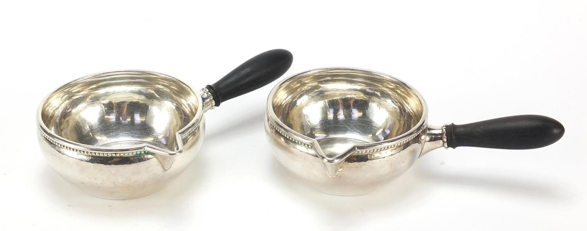 Georg Jensen, pair of Danish 925S silver porringers with ebony handles, 16.5cm in length, 304.0g