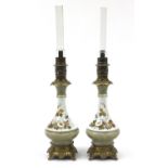 Pair of porcelain and brass mounted oil lamps having glass chimneys, 66cm high