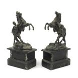 Pair of spelter Marley horse and trainer figures raised on black slate bases, 31cm high