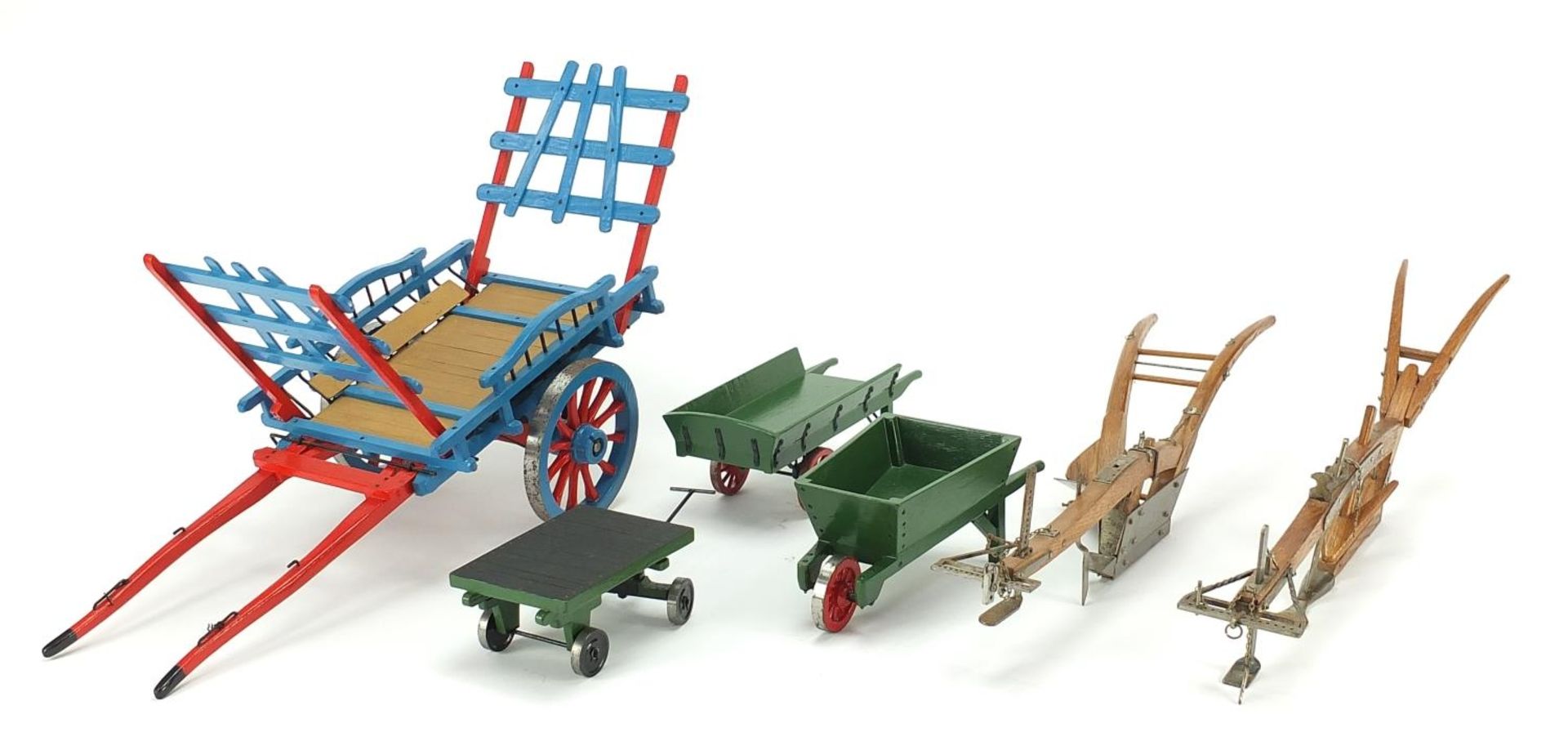 Scratch built metal and wood models of carts, wheelbarrows and ploughing implements, the largest